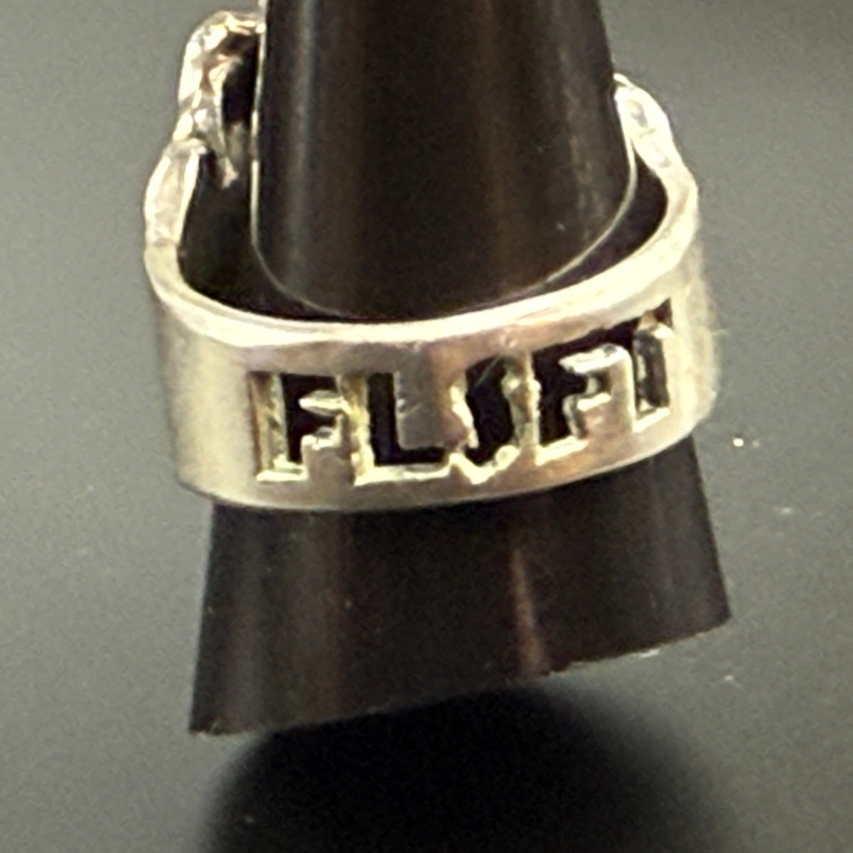 A silver skull ring with FLSFT' engraved on the band.