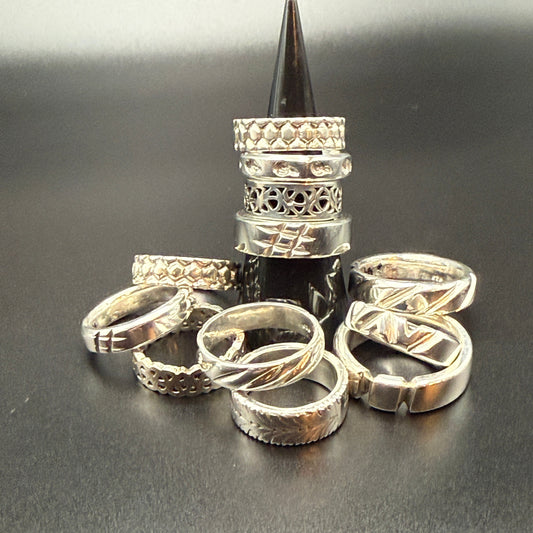 A group of sterling silver rings with various textured, filigree, and twisted band designs.