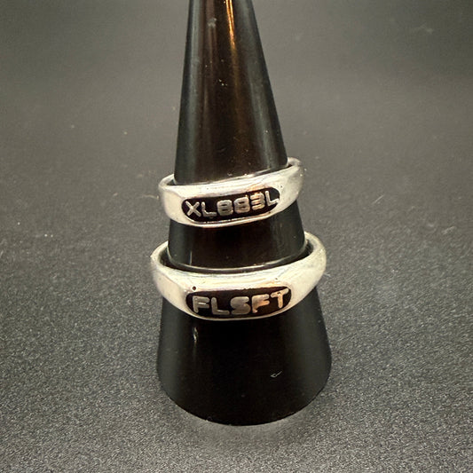 Two narrow sterling silver signet rings with custom embedded lettering reading "XL883L" and 'FLSFT'