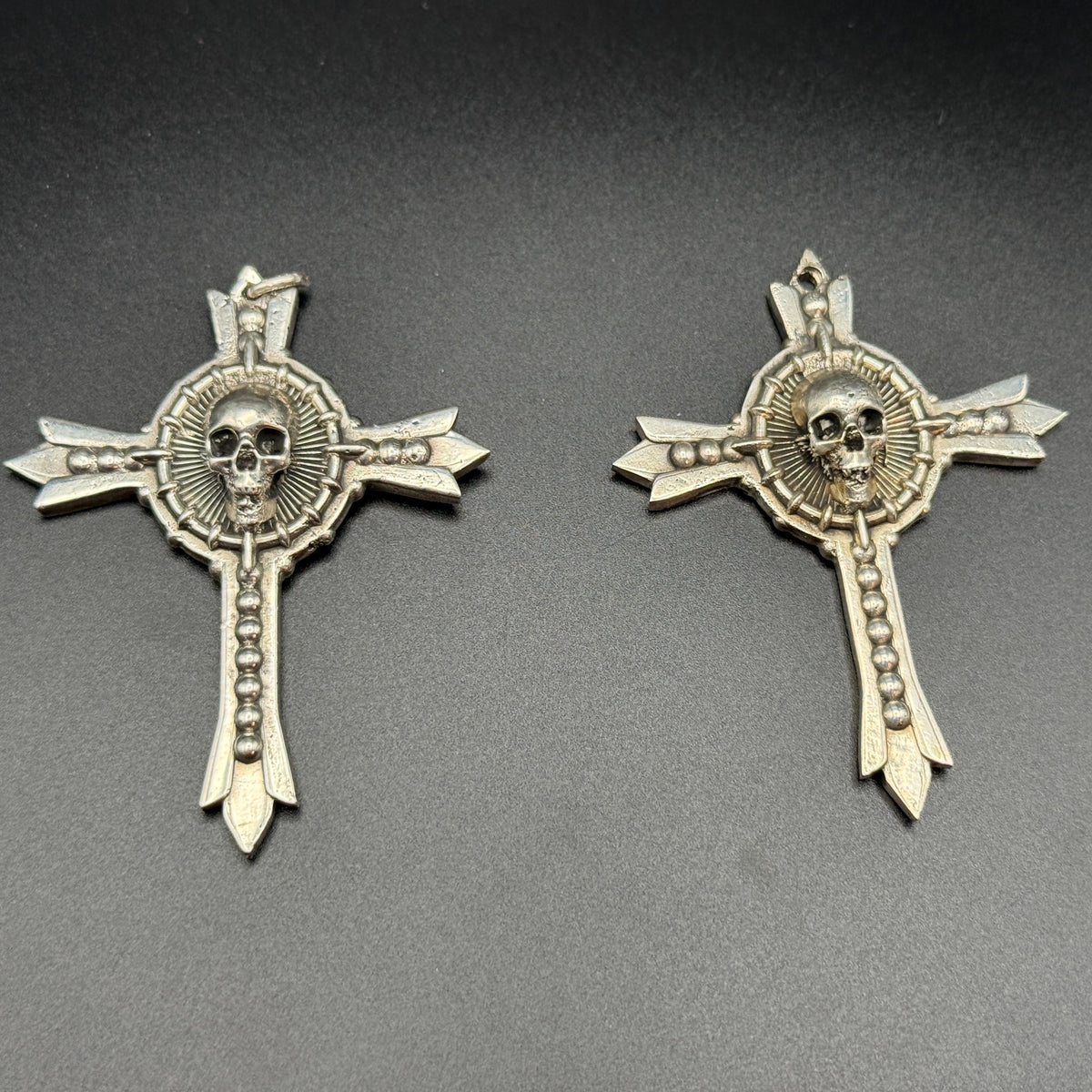 Two sterling silver gothic cross pendants with skull details.