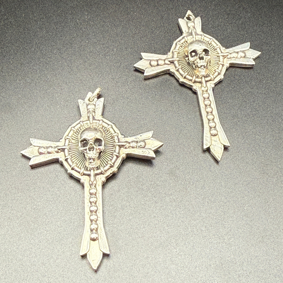 Two sterling silver gothic cross pendants with skull details.