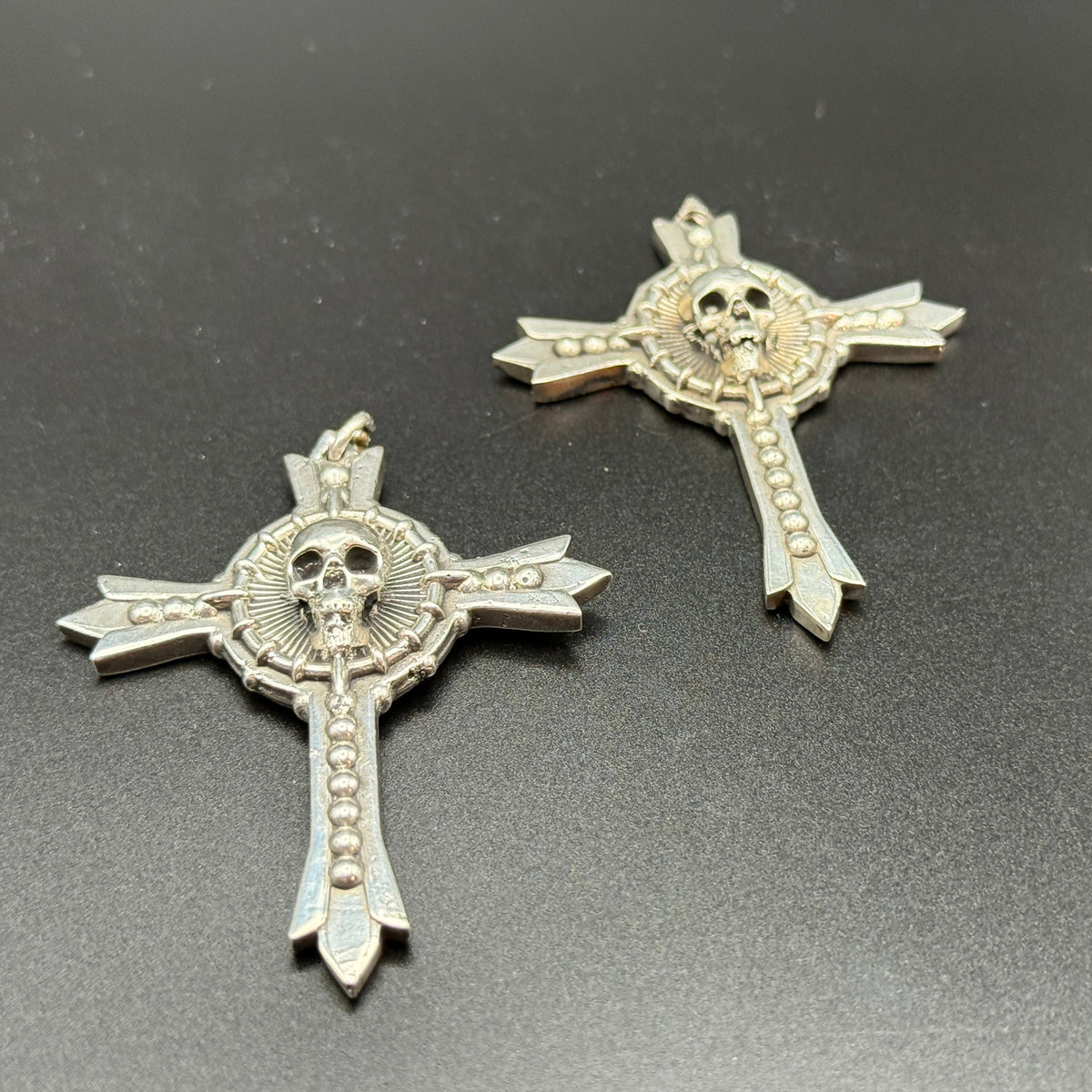 Two sterling silver gothic cross pendants with skull details.