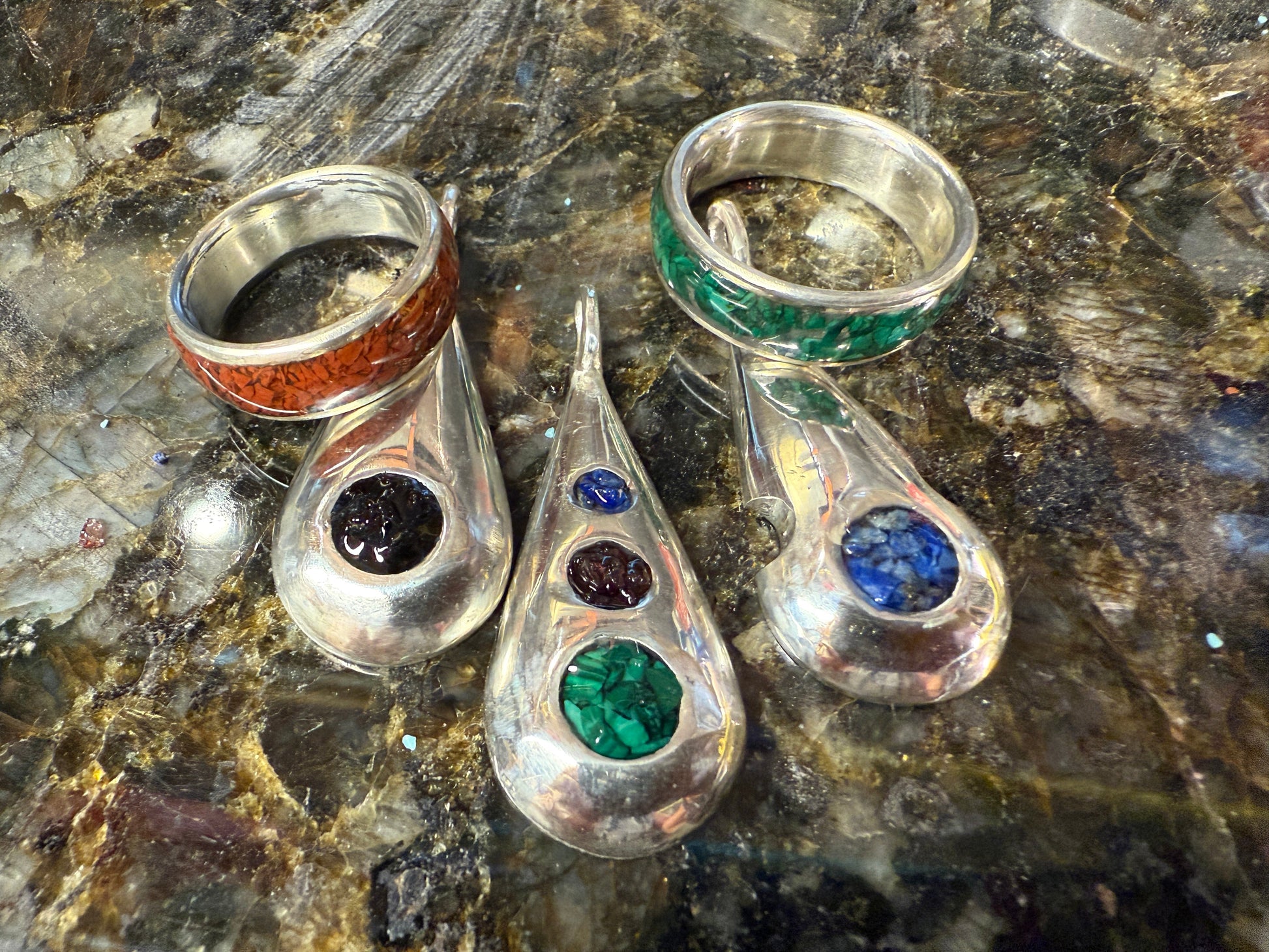 Collection of handmade rings and pendants with embedded natural stone chips