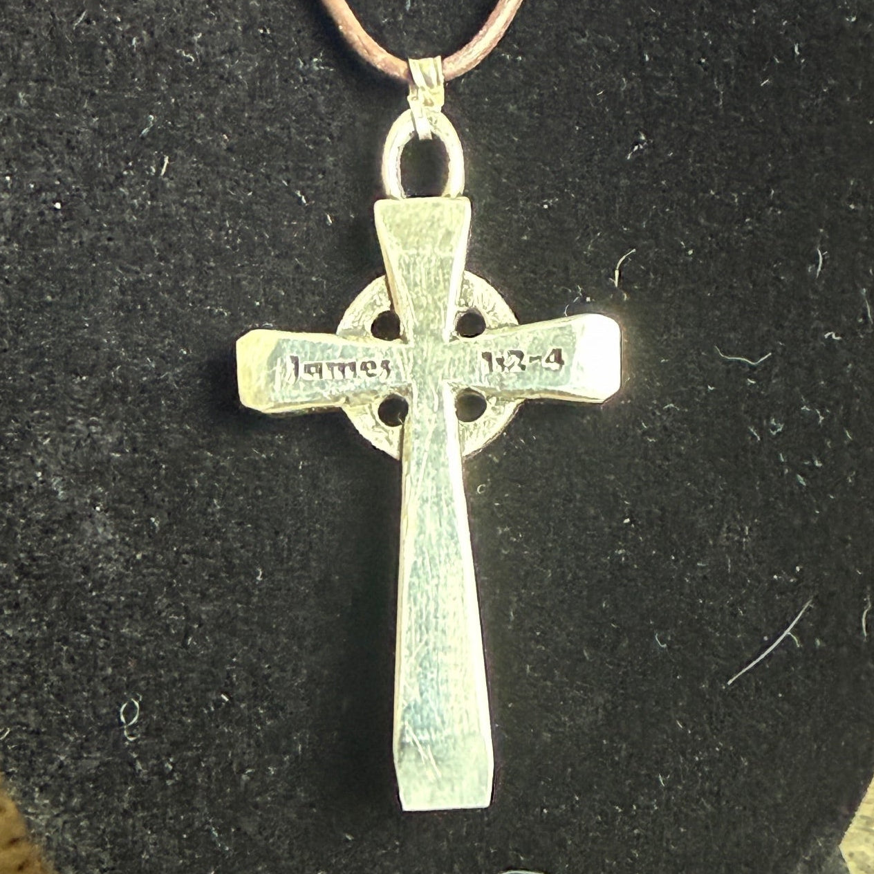 Silver cross pendant on a black background