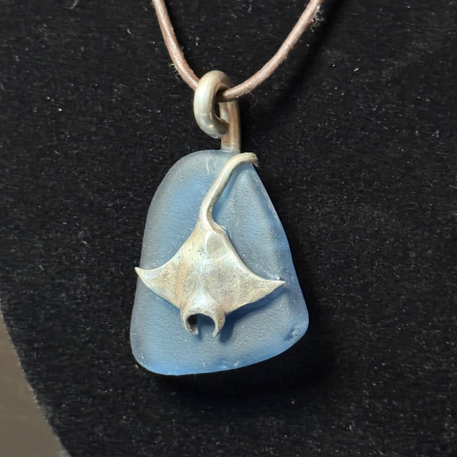 Large blue sea glass pendant with a silver stingray.