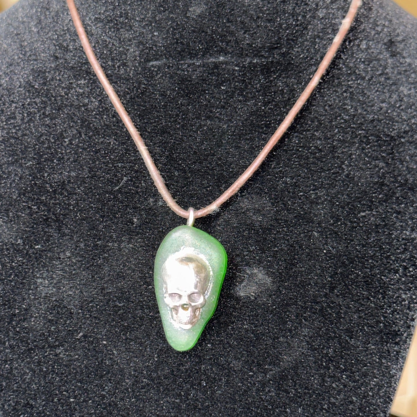 Medium green sea glass pendant with a silver skull.