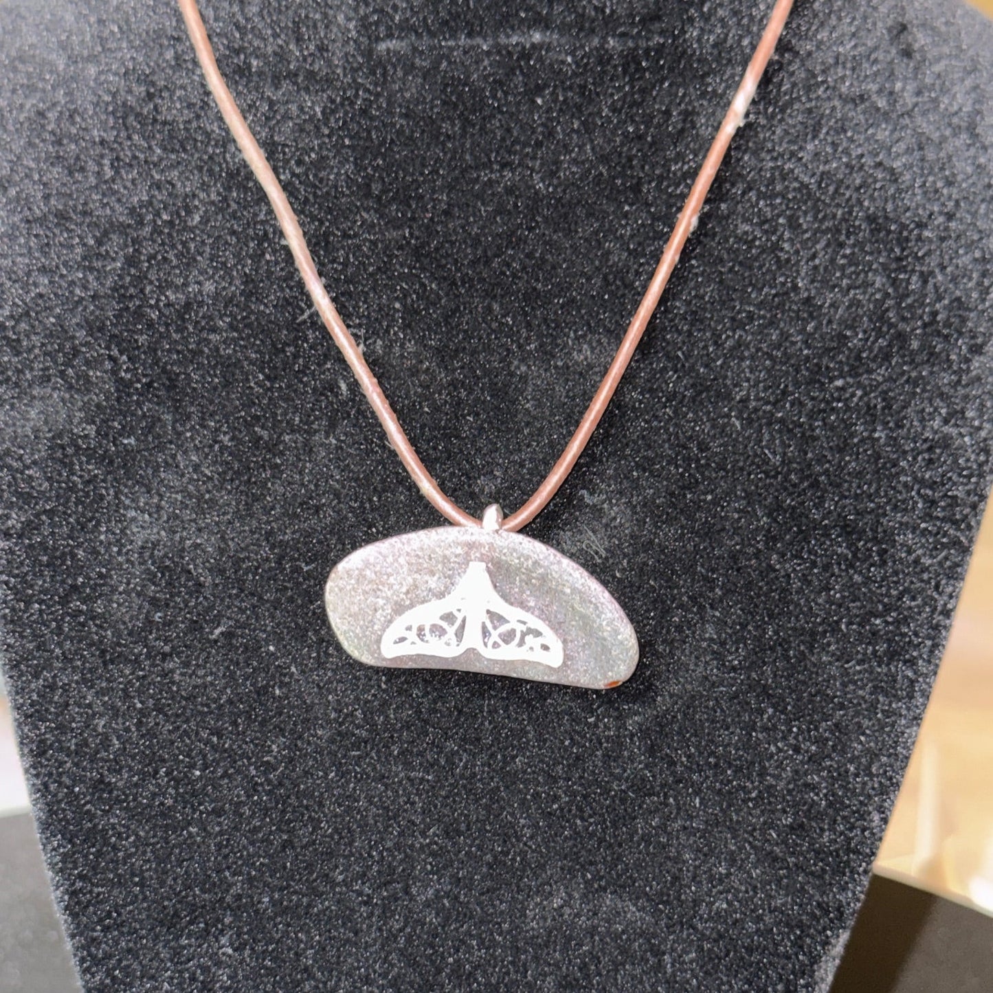 Medium brown sea glass pendant with a silver whale tail.