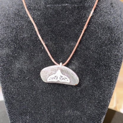 Medium brown sea glass pendant with a silver whale tail.