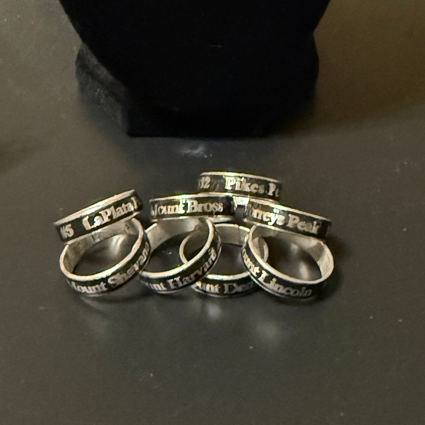 Set of silver rings with engraved text on a dark surface