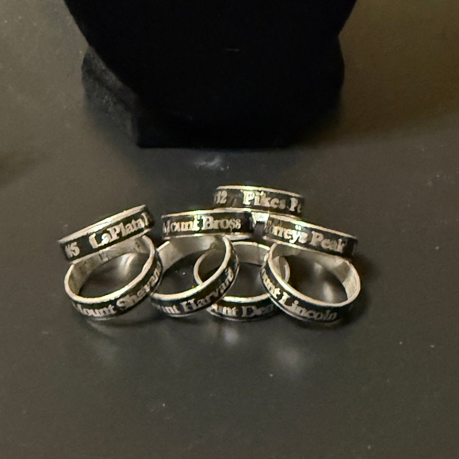 Set of silver rings with engraved text on a dark surface