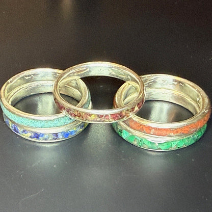 Five silver rings with colorful inlay on a black background